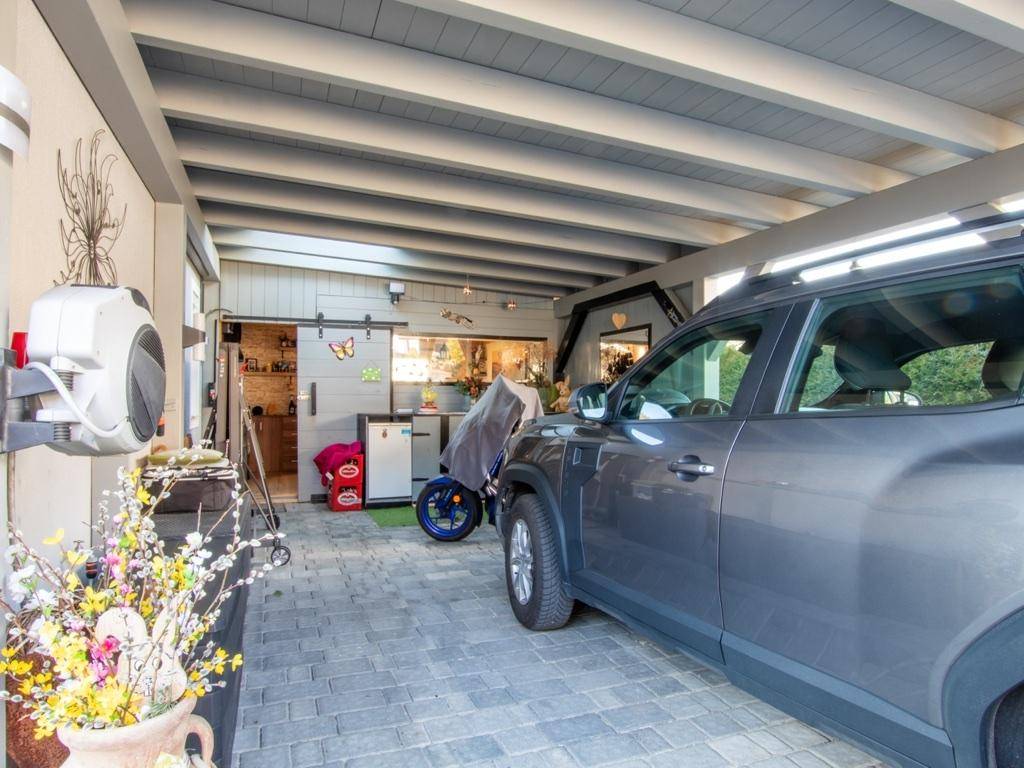 Überdachter Carport mit Stellplatz für ein Fahrzeug und Zugang zum Haus.