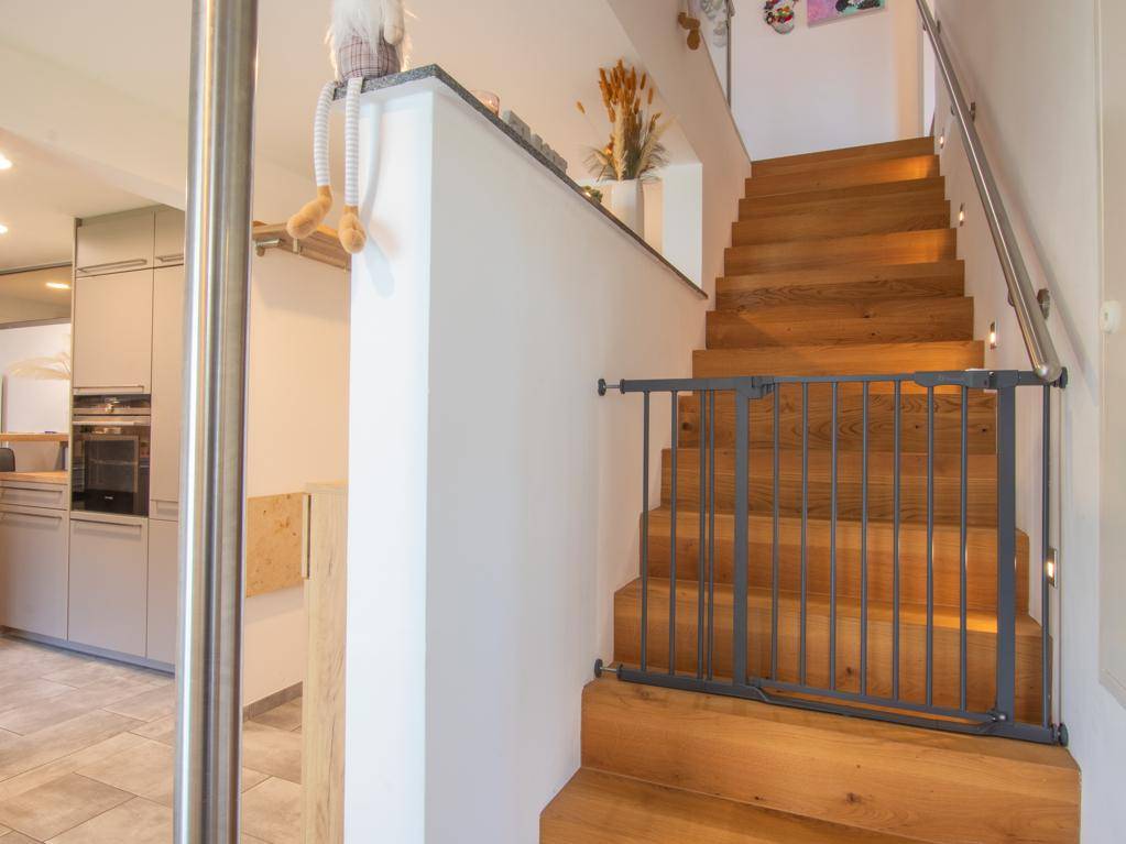 Holztreppe mit Kinderschutzgitter, die in das obere Stockwerk führt.