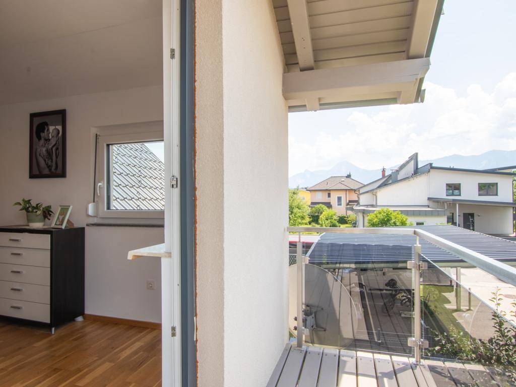 Balkon mit Glasgeländer und Holzboden, der einen weiten Blick auf die Berge ermöglicht.