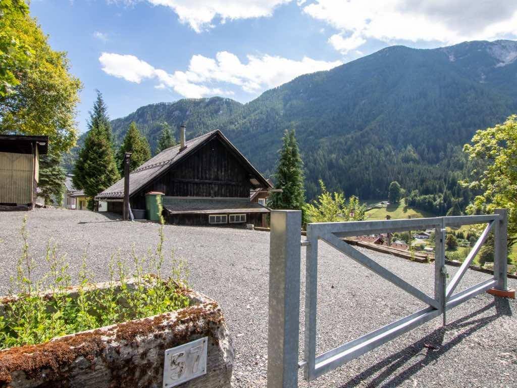 Rustikales Holzhaus in alpiner Umgebung mit beeindruckendem Bergblick und Schotterzufahrt.