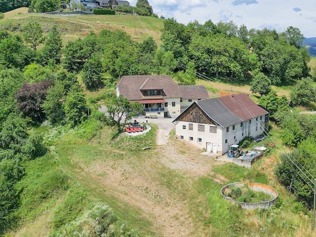 Weitläufige Luftaufnahme des Anwesens mit Gebäuden, großer Rasenfläche und ländlicher Umgebung.