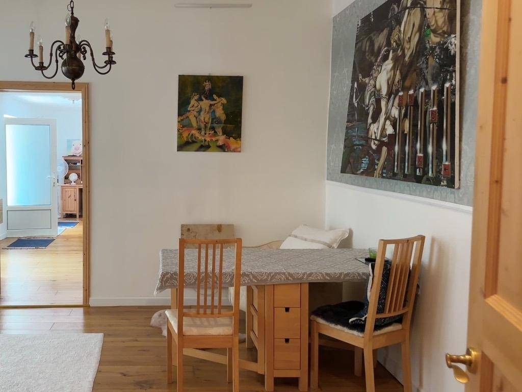 Essbereich mit Holztisch, Stühlen und Kunstwerken an den Wänden.
