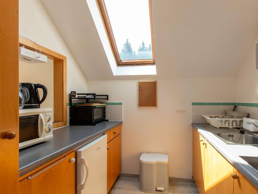 Funktionale Küche im Dachgeschoss mit Dachfenster, Mikrowelle und Kühlschrank.
