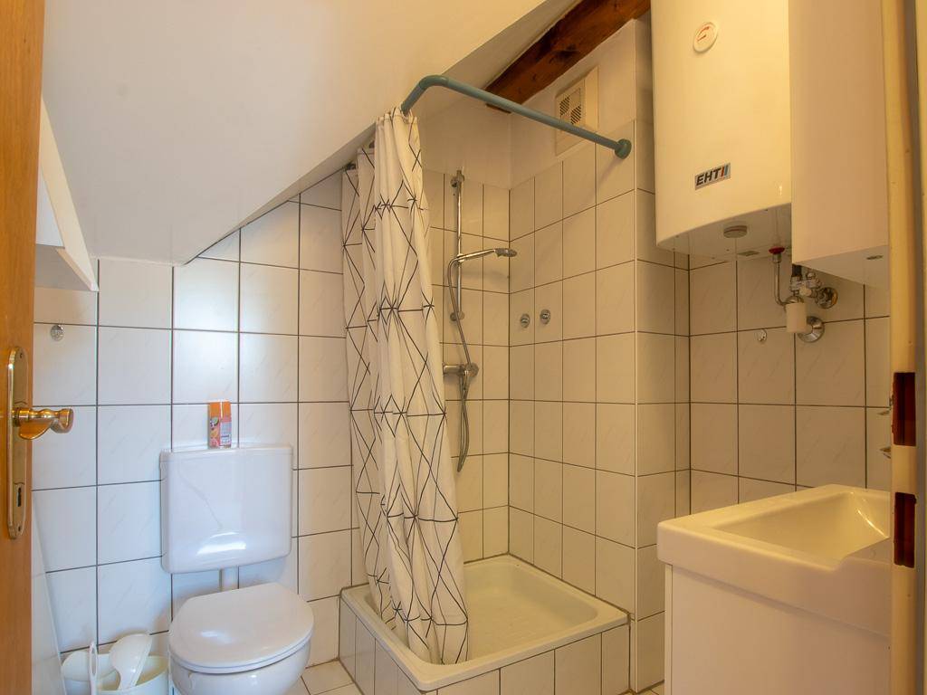 Kleines Badezimmer mit Dusche, WC, Waschbecken und weißen Fliesen.