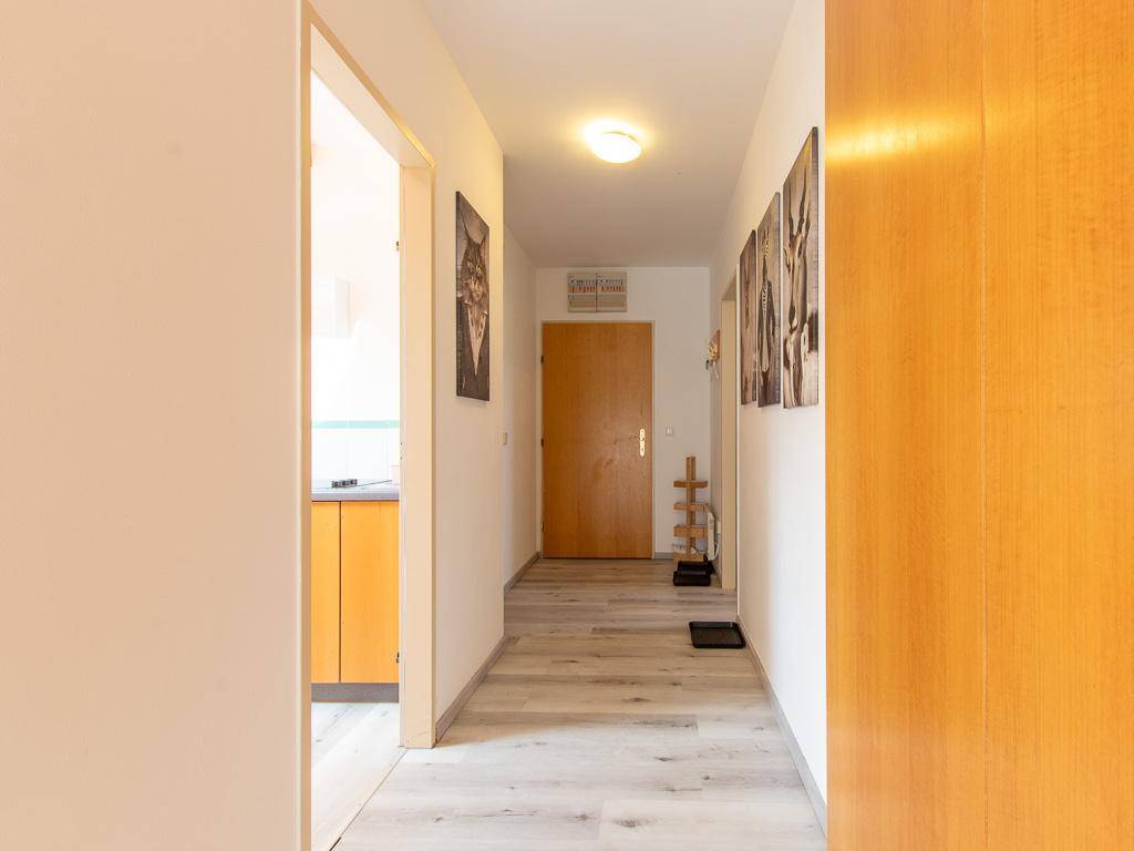 Heller Flur mit Laminatboden, Holztüren und Zugang zu den Zimmern.