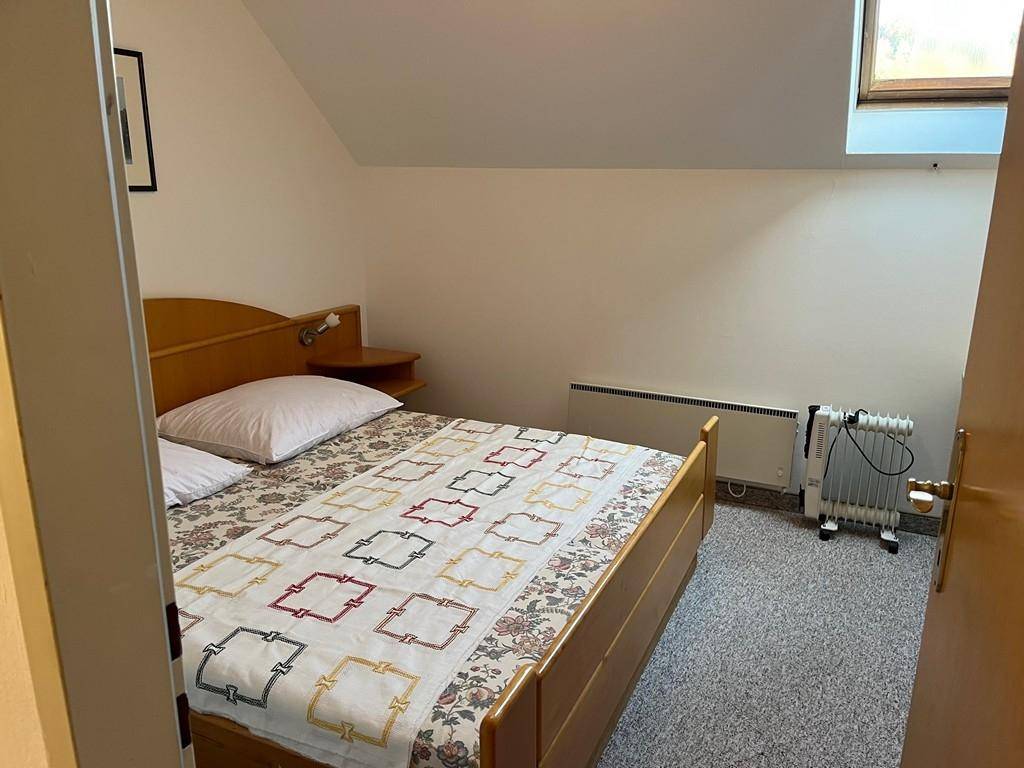 Gemütliches Schlafzimmer mit Doppelbett, Teppichboden und Dachfenster.