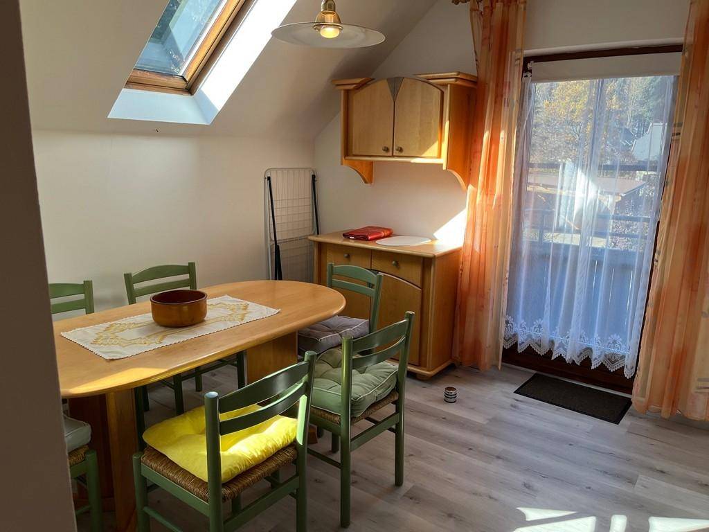 Essbereich im Dachgeschoss mit Holztisch, Stühlen und Zugang zum Balkon.