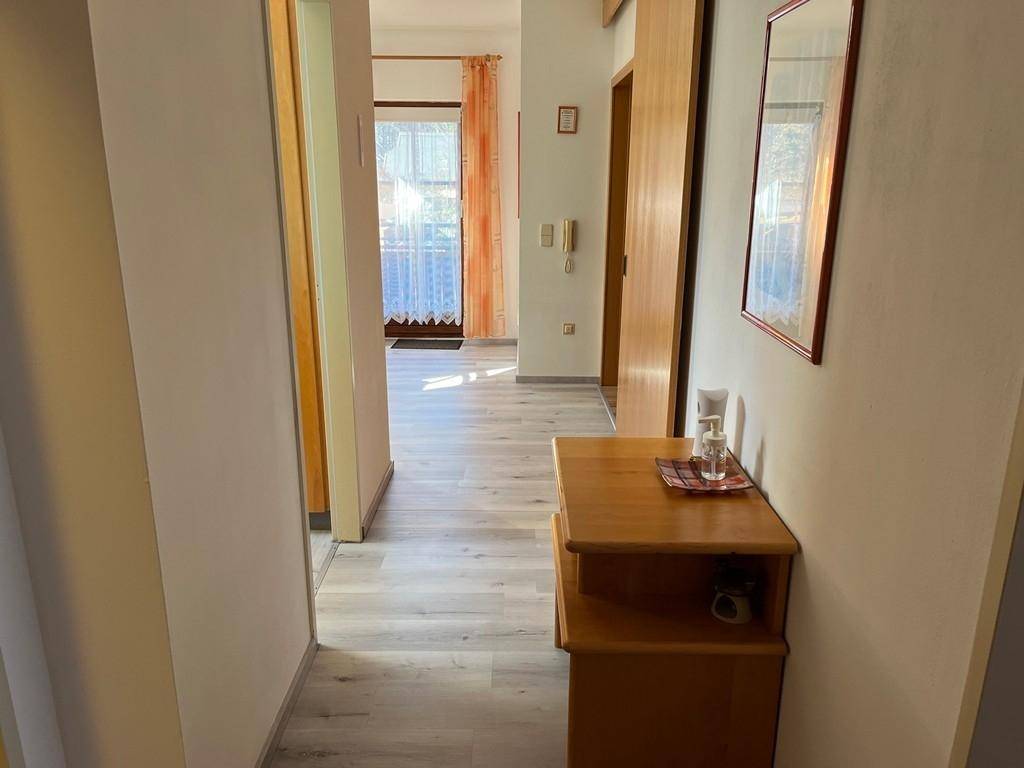 Heller Flur mit Laminatboden, Holztüren und Blick zum Eingangsbereich.