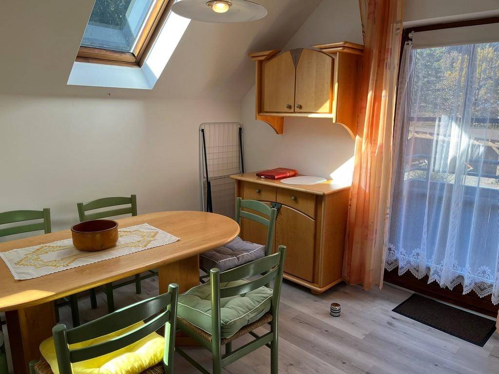 Heller Essbereich im Dachgeschoss mit Holztisch, Stühlen und Balkonzugang.