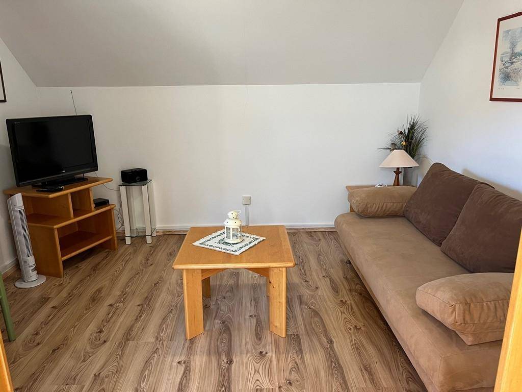 Wohnzimmer mit braunem Sofa, Couchtisch und Fernseher.