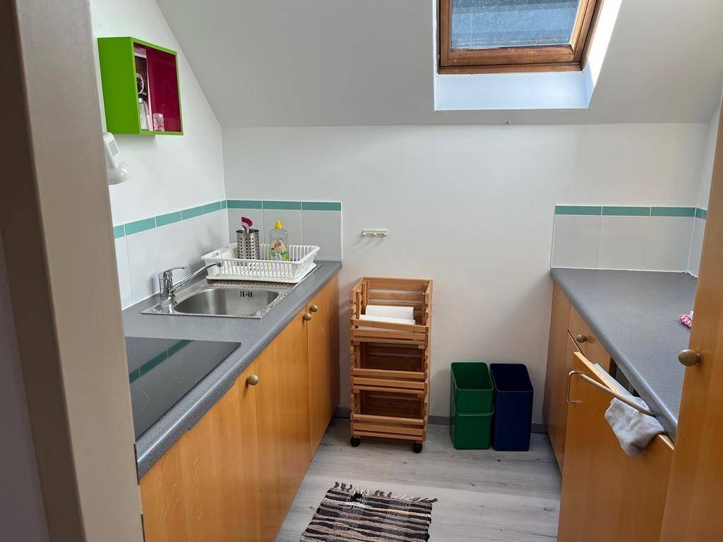 Kleine Küche mit Holzschränken, Spüle und Dachfenster.
