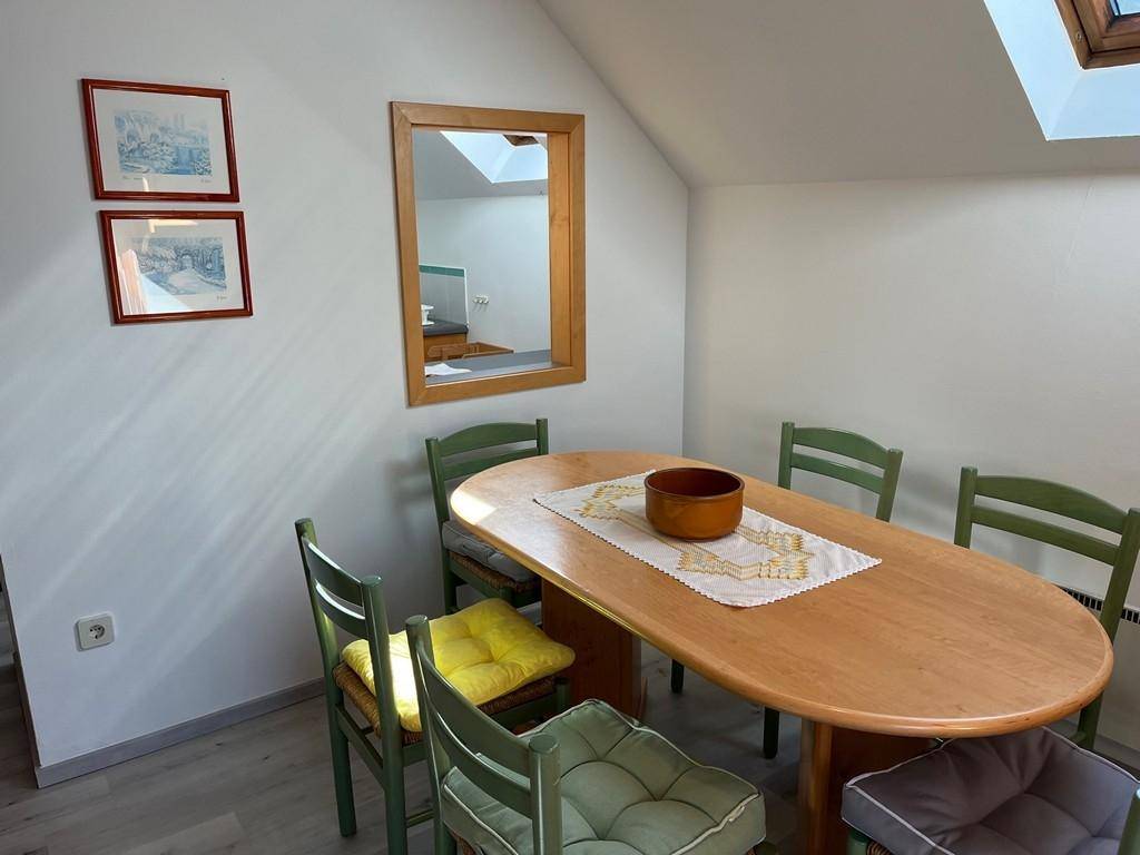 Essbereich mit Holztisch, grünen Stühlen und Spiegel an der Wand.