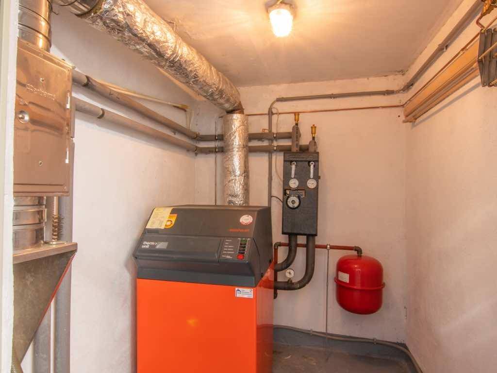 Heizungsraum im Keller mit moderner Heizungsanlage und sichtbaren Rohren.