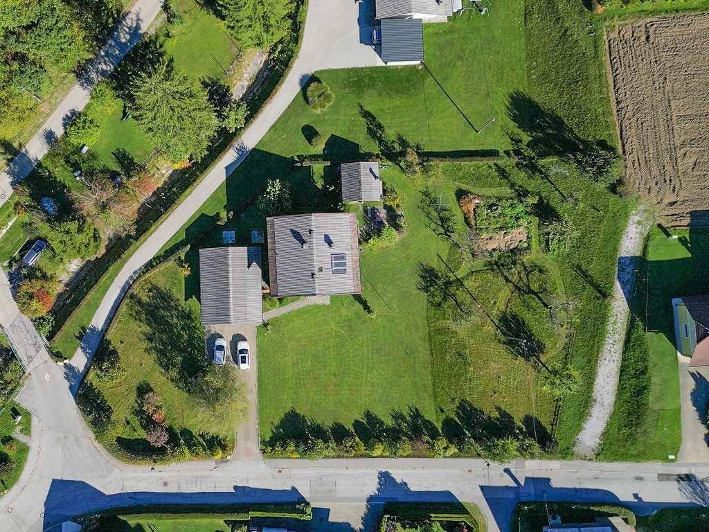 Luftaufnahme eines Grundstücks mit Wohnhaus, Gartenbereich und angrenzenden Feldern und Straßen.