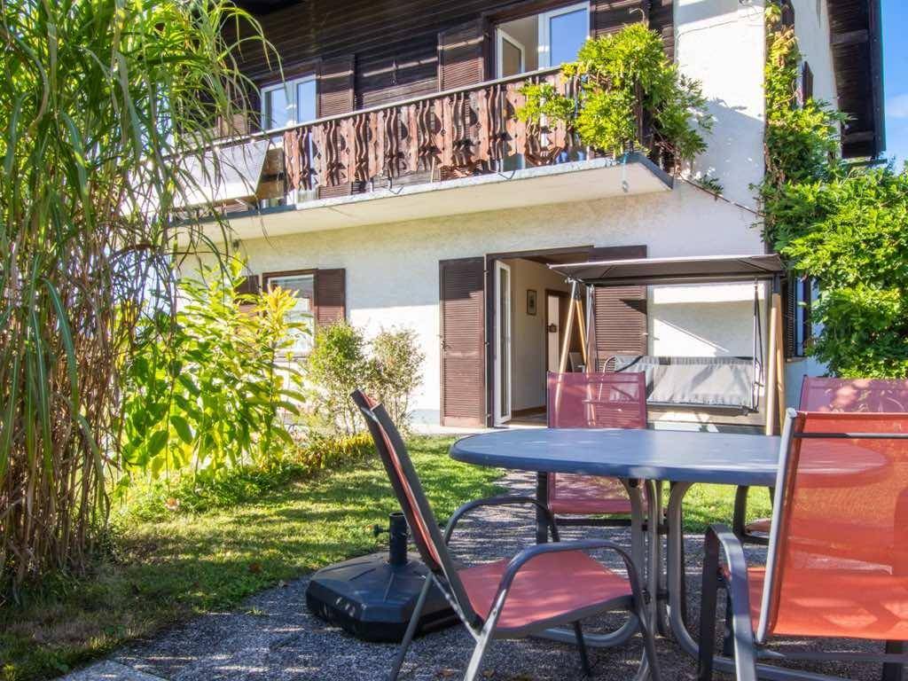 Gemütlicher Außenbereich mit Terrassenmöbeln und Blick auf das Haus mit Balkon und Garten.