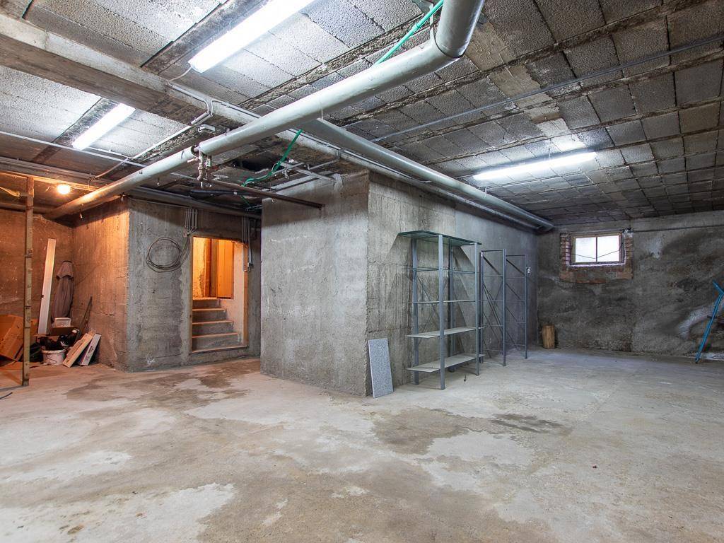 Geräumiger Kellerraum mit Betonboden, sichtbaren Rohren und einem kleinen Fenster.