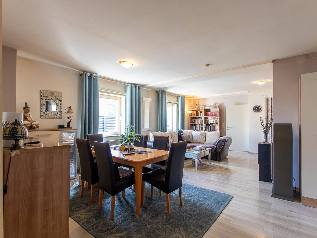 Geräumiger Wohn-Essbereich mit Holzboden, großem Esstisch und gemütlicher Sitzecke.