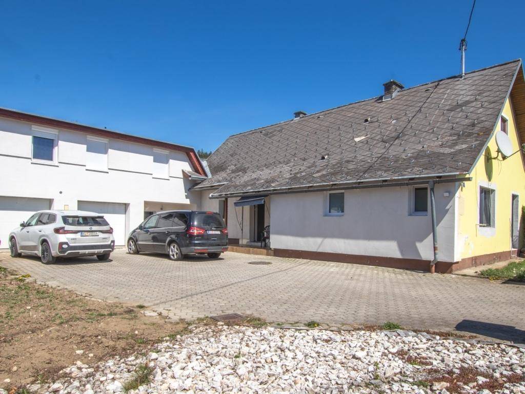 Außenansicht des Hauses mit gepflasterter Einfahrt und zwei geparkten Autos.