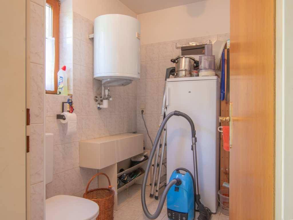 Praktischer Hauswirtschaftsraum mit Boiler, WC und Stauraum für Reinigungsgeräte.