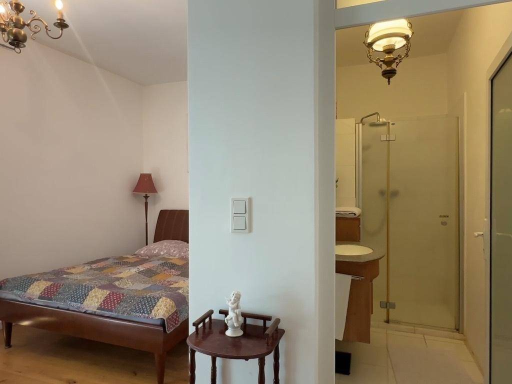 Schlafzimmer mit Holzbett und direktem Zugang zu einem Badezimmer mit Dusche.