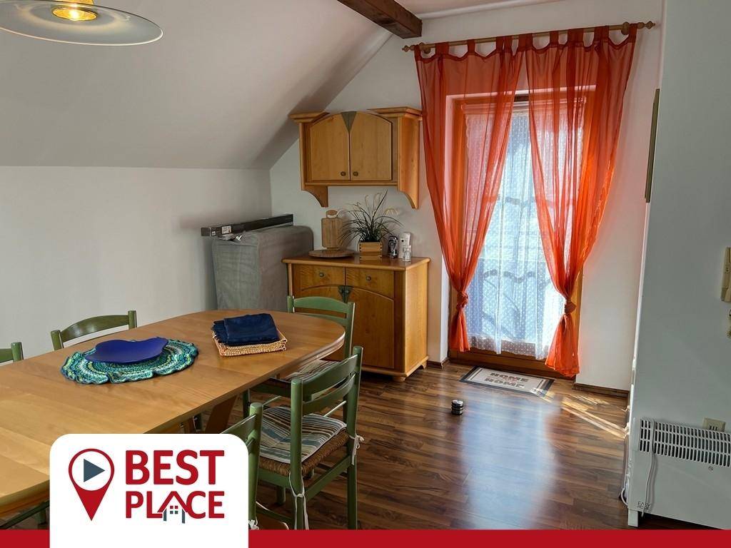 Gemütlicher Essbereich im Dachgeschoss mit Holzbalken, Holzboden und Zugang zum Balkon.