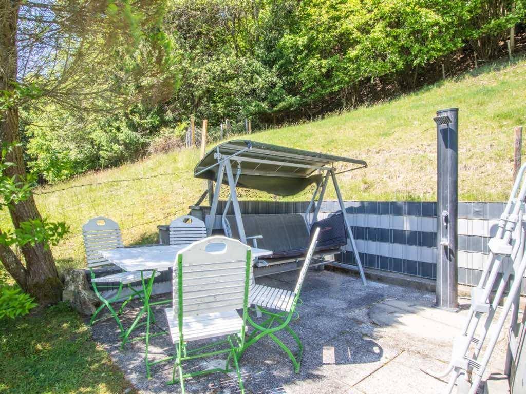 Gemütlicher Außenbereich mit Sitzgelegenheiten, Hollywoodschaukel und Außendusche im Grünen.