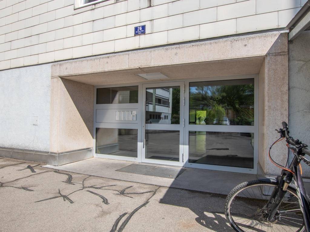 Nahaufnahme des Hauseingangs mit Glastüren und Gegensprechanlage.
