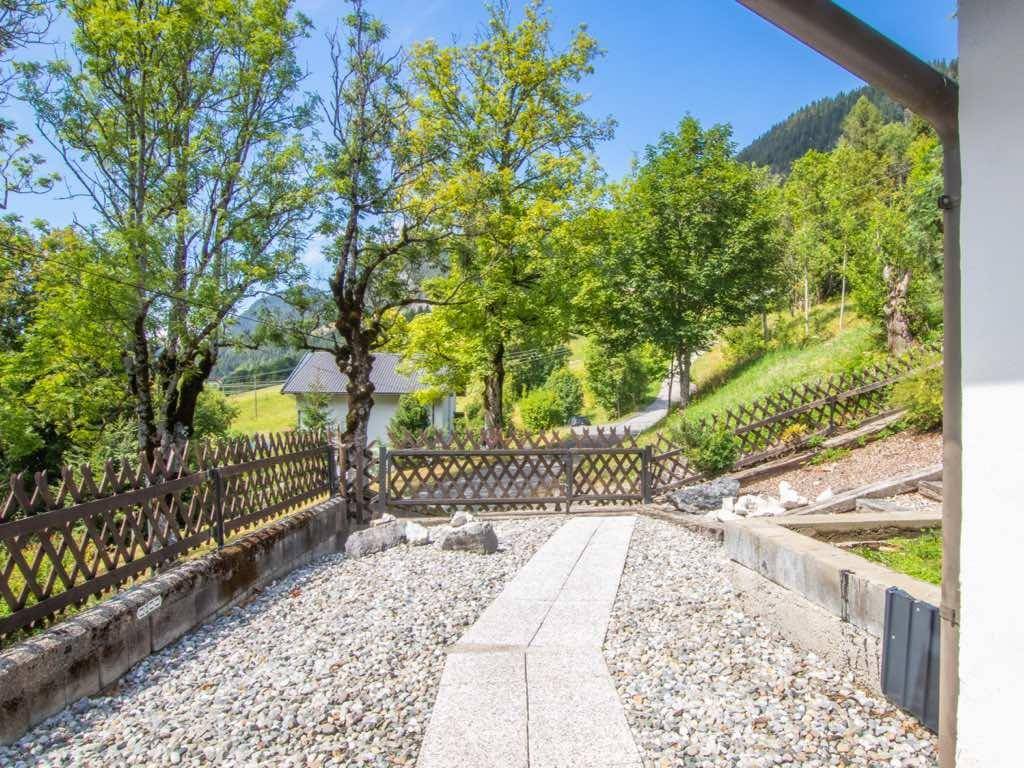 Kiesweg führt zu einem Haus, umgeben von einem Holzzaun und Bäumen mit Bergblick.