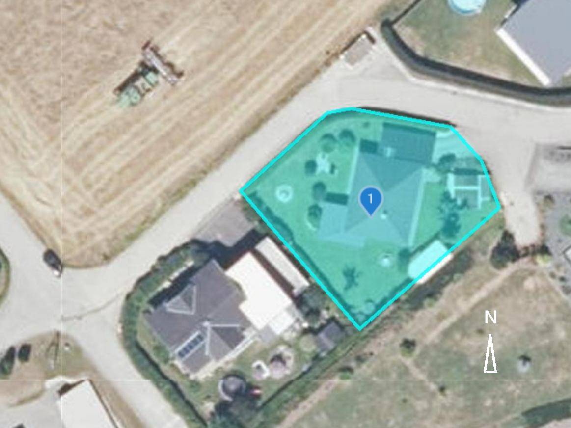 Luftaufnahme eines Grundstücks mit Einfamilienhaus und Garten, umgeben von Feldern und weiteren Häusern.