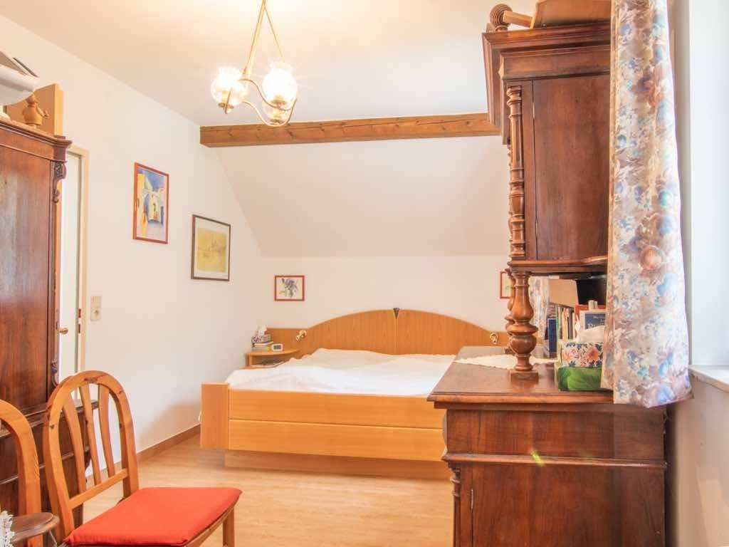 Helles Schlafzimmer mit Doppelbett, Holzbalken und traditionellen Möbeln.