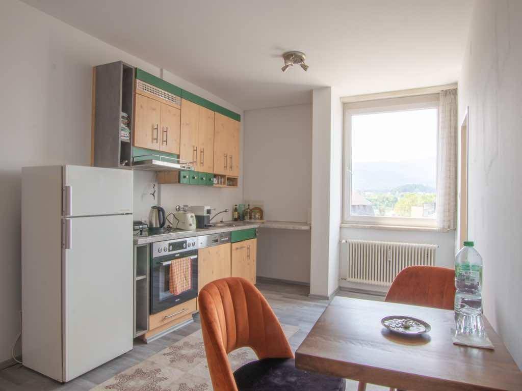 Funktionale Küche mit Holzelementen, Essbereich und Fenster mit Blick auf die umliegende Berglandschaft.