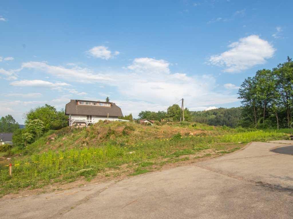 Blick auf ein begrüntes Hanggrundstück mit einem Haus auf der Anhöhe unter strahlend blauem Himmel.