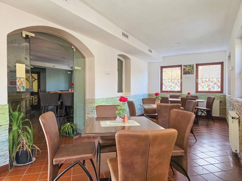 Heller Essbereich mit braunen Stühlen, Holztischen und dekorativen Fenstern.