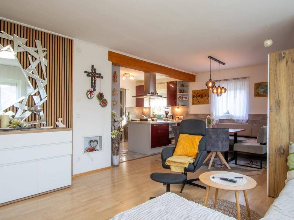 Offener Wohn- und Essbereich mit Holzboden und Blick in die moderne Küche.