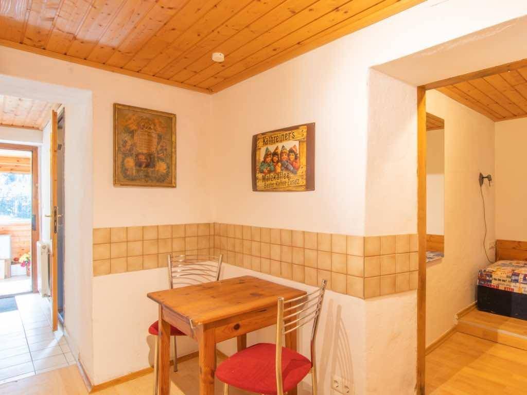 Kleiner Essbereich mit Holztisch, Stühlen und gefliester Wandvertäfelung unter einer Holzdecke.