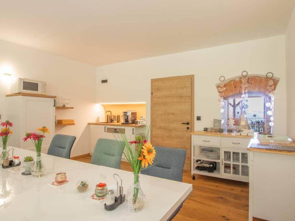 Geräumiger Essbereich mit langem Tisch und einer kleinen Küchenzeile im Hintergrund.