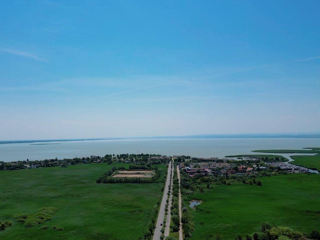 Weitläufige Luftaufnahme einer Seenlandschaft mit grünen Feldern und einer Straße.