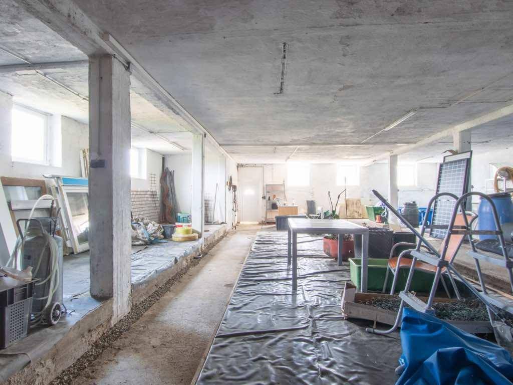 Geräumiger, unfertiger Kellerraum mit Betonboden und Säulen, genutzt als Lagerfläche.