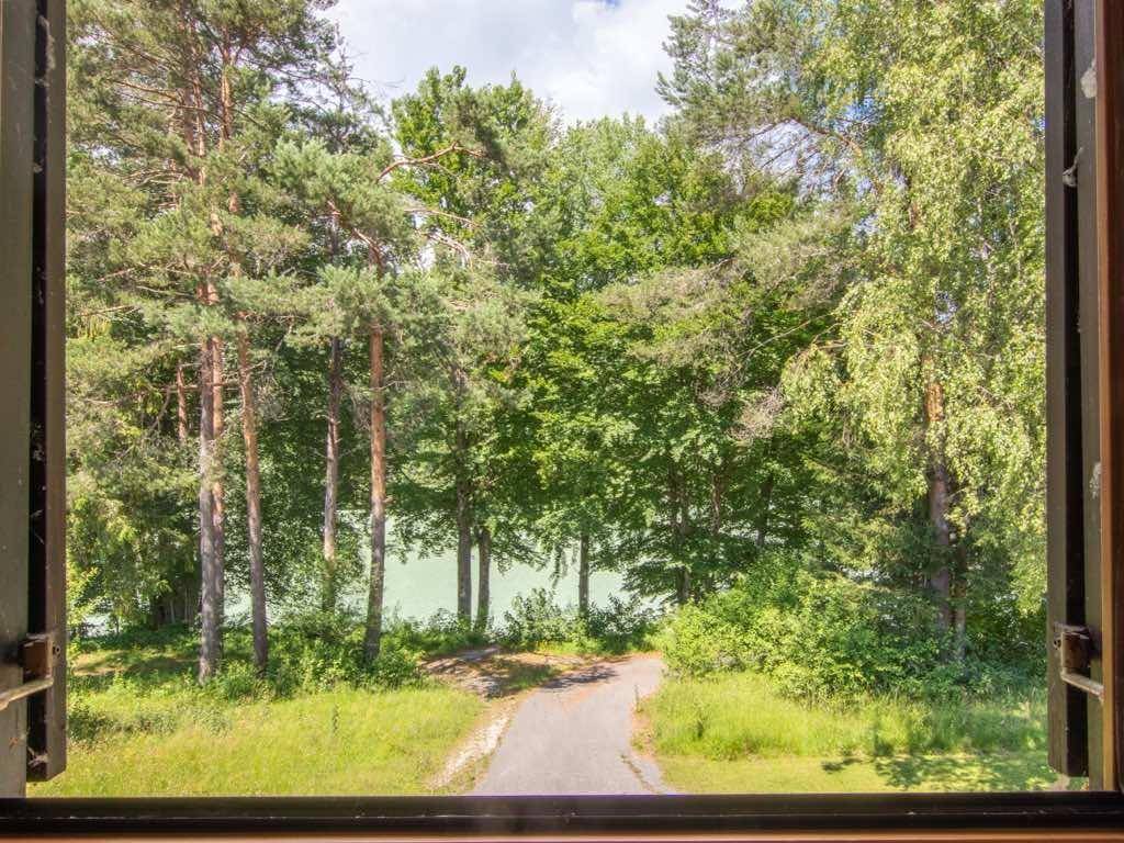 Blick aus einem Fenster auf einen malerischen See, umgeben von dichten Wäldern und unberührter Natur.