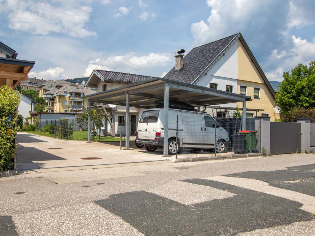 Carport mit Stellplatz für ein Fahrzeug neben dem Haus und angrenzendem Zaun.