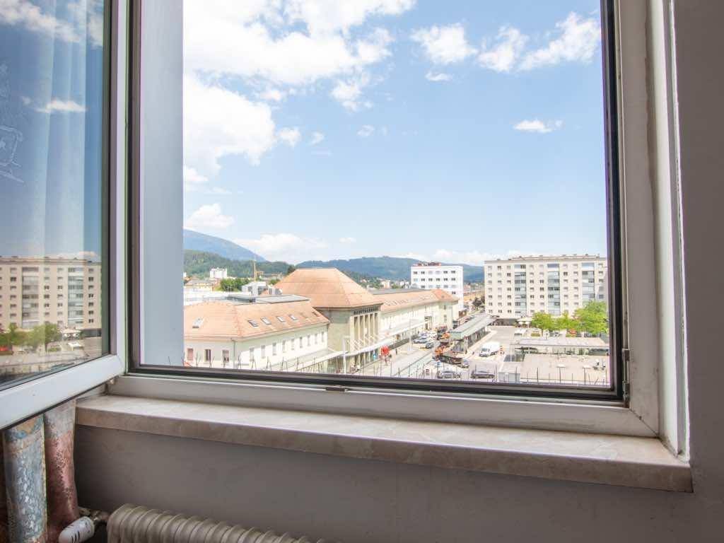 Panoramablick aus dem Fenster über die belebte Stadtstraße und die majestätischen Berge.