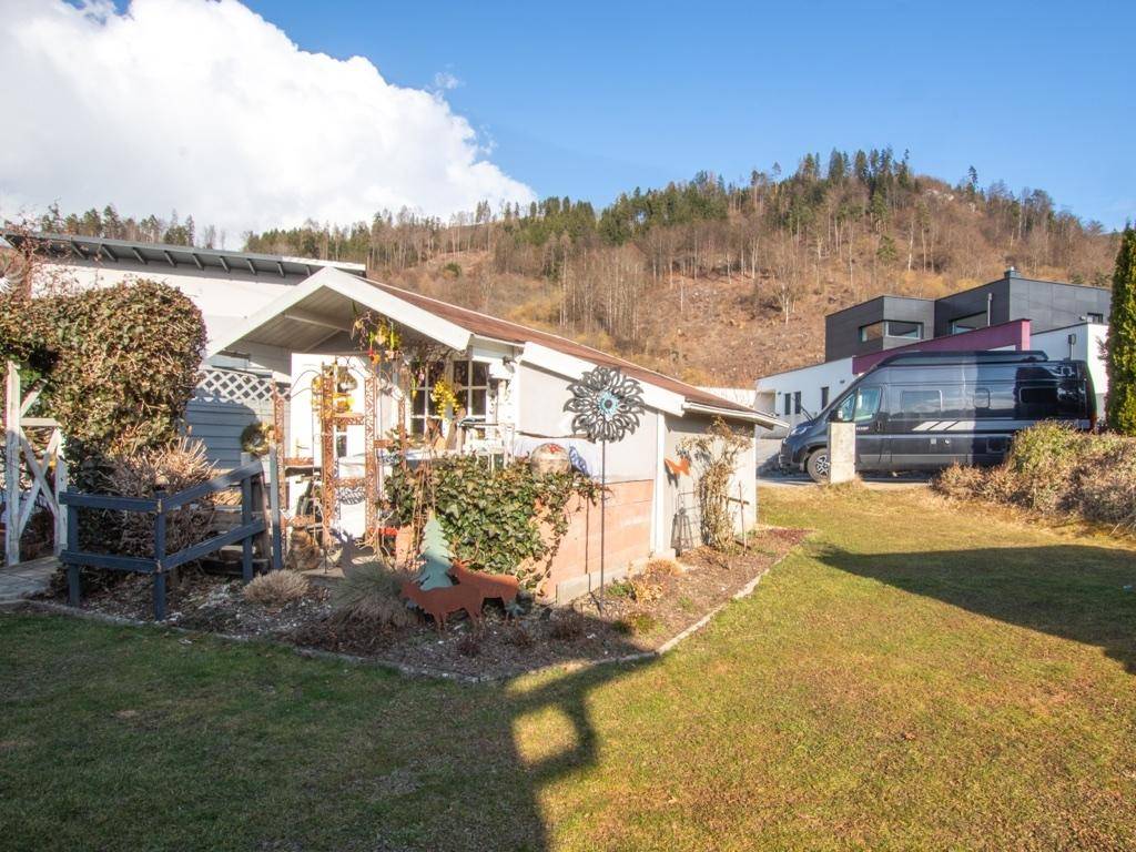 Weißes Gartenhaus mit dekorativen Elementen und gepflegtem Gartenbereich.
