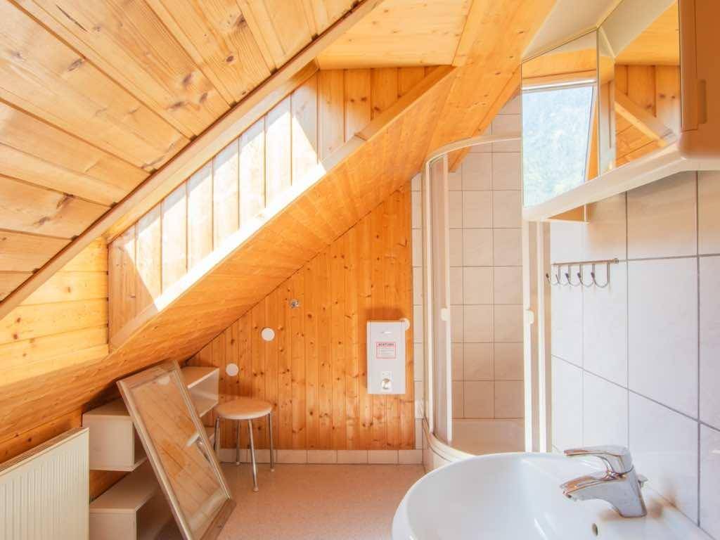 Helles Badezimmer im Dachgeschoss mit Holzwänden, Duschkabine, Waschbecken und Dachfenster.