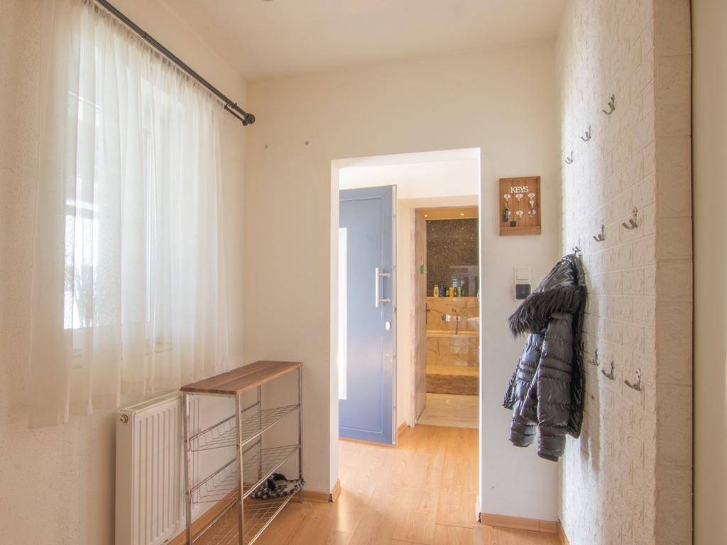 Heller Flur mit Fenster, Heizkörper, Schuhregal und Garderobe, führt zu weiteren Räumen.