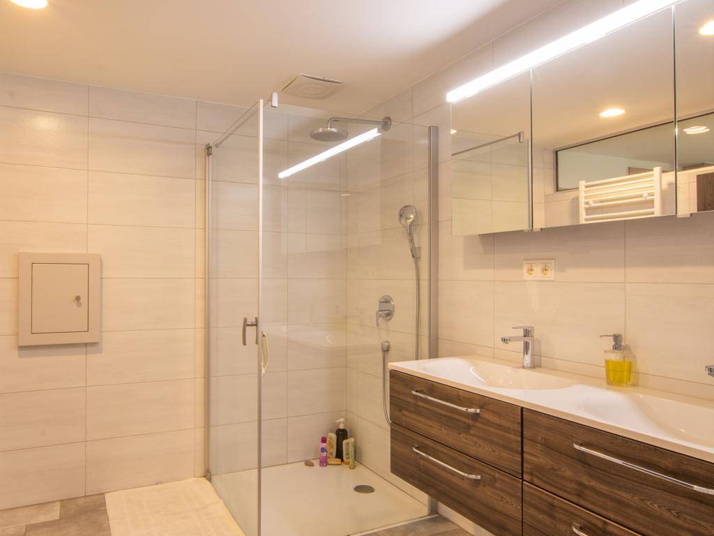 Helles Badezimmer mit begehbarer Dusche, Einzelwaschbecken und Spiegelschrank.