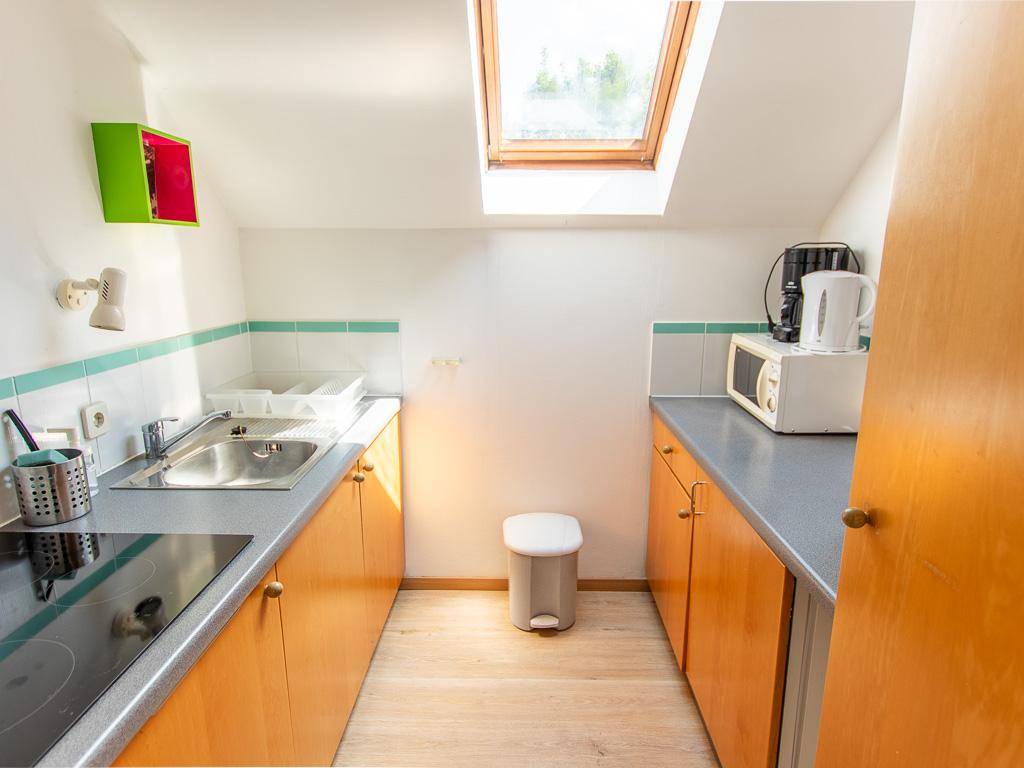 Funktionale Küchenzeile im Dachgeschoss mit Dachfenster, Kochfeld und Mikrowelle.