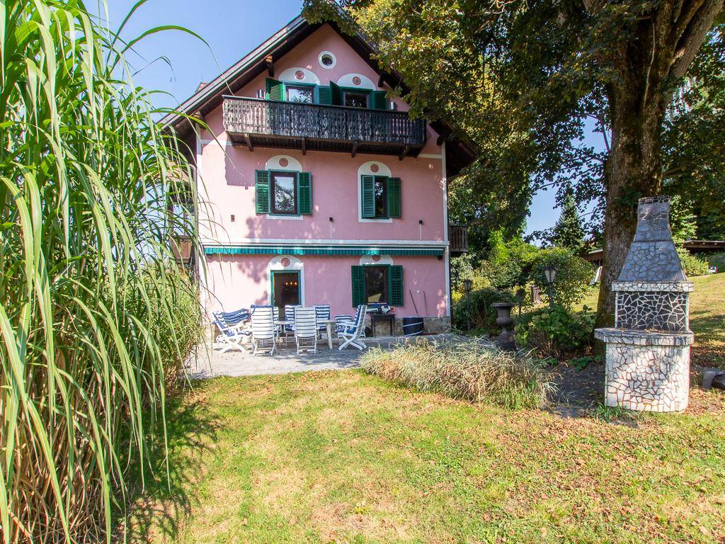 Hinterhof des rosa Hauses mit Terrasse, Gartenmöbeln und gemauertem Grillplatz.