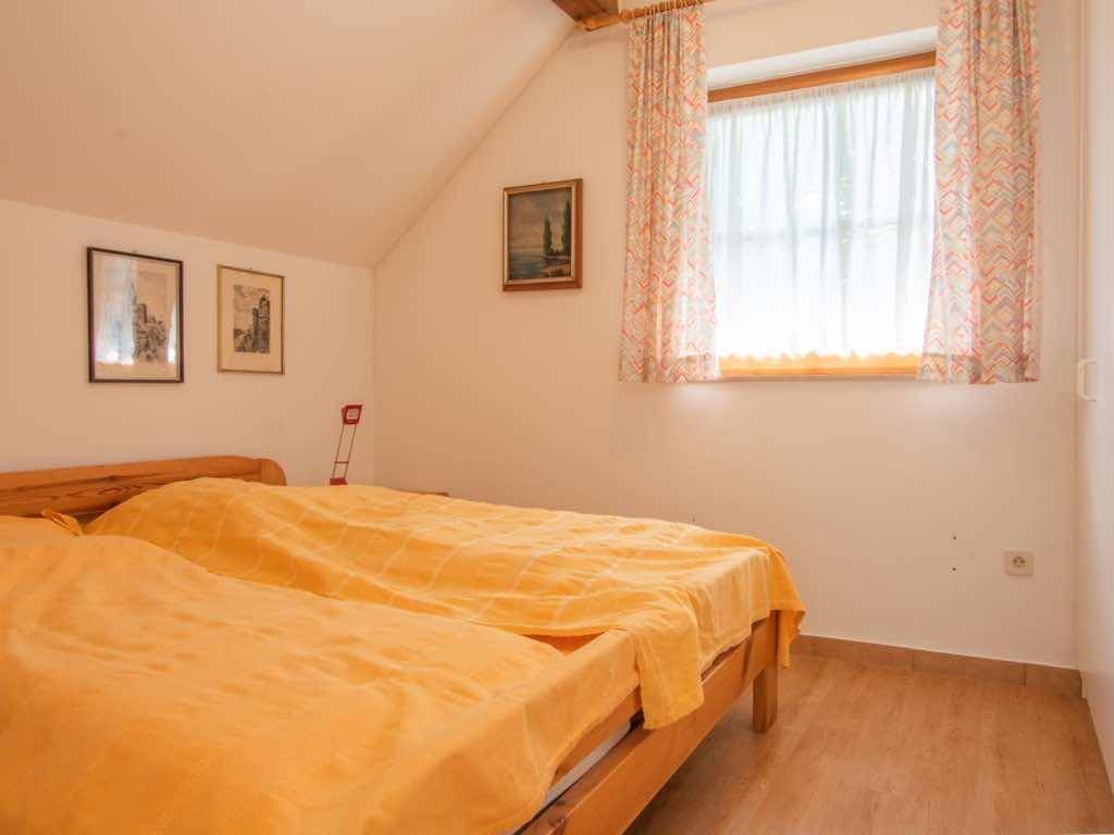 Gemütliches Schlafzimmer mit zwei Einzelbetten und Fenster mit Blick ins Grüne.