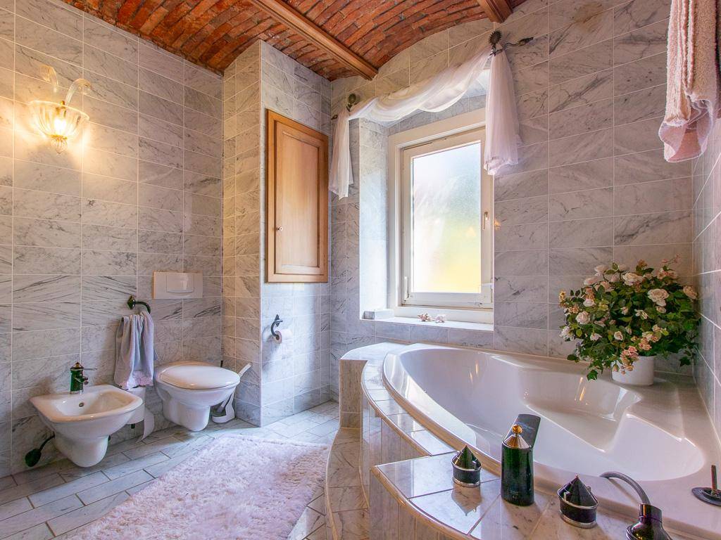 Elegantes Badezimmer mit Eckbadewanne, Bidet, WC und Marmorfliesen unter einer Ziegelgewölbedecke.