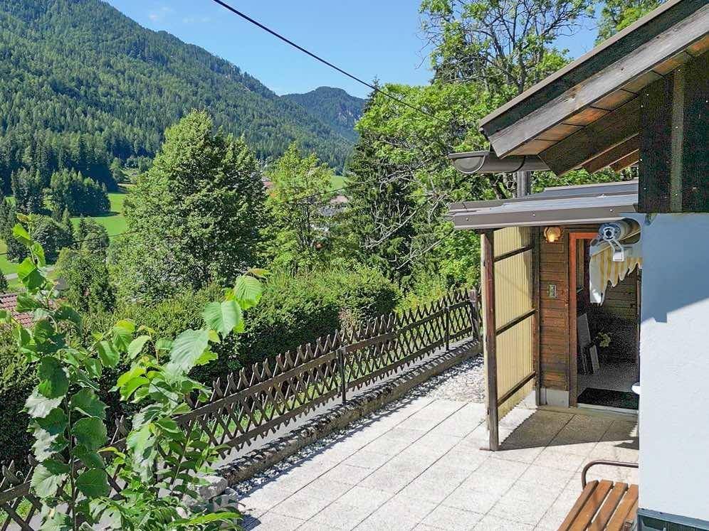 Gepflasterte Terrasse mit Holzbank und weitem Blick auf die umliegende Berglandschaft.